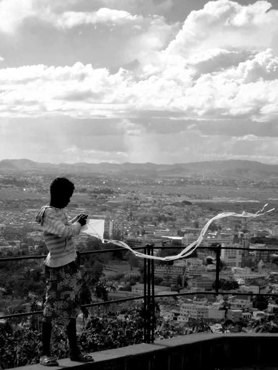 Boy flying a kite with a view of the city