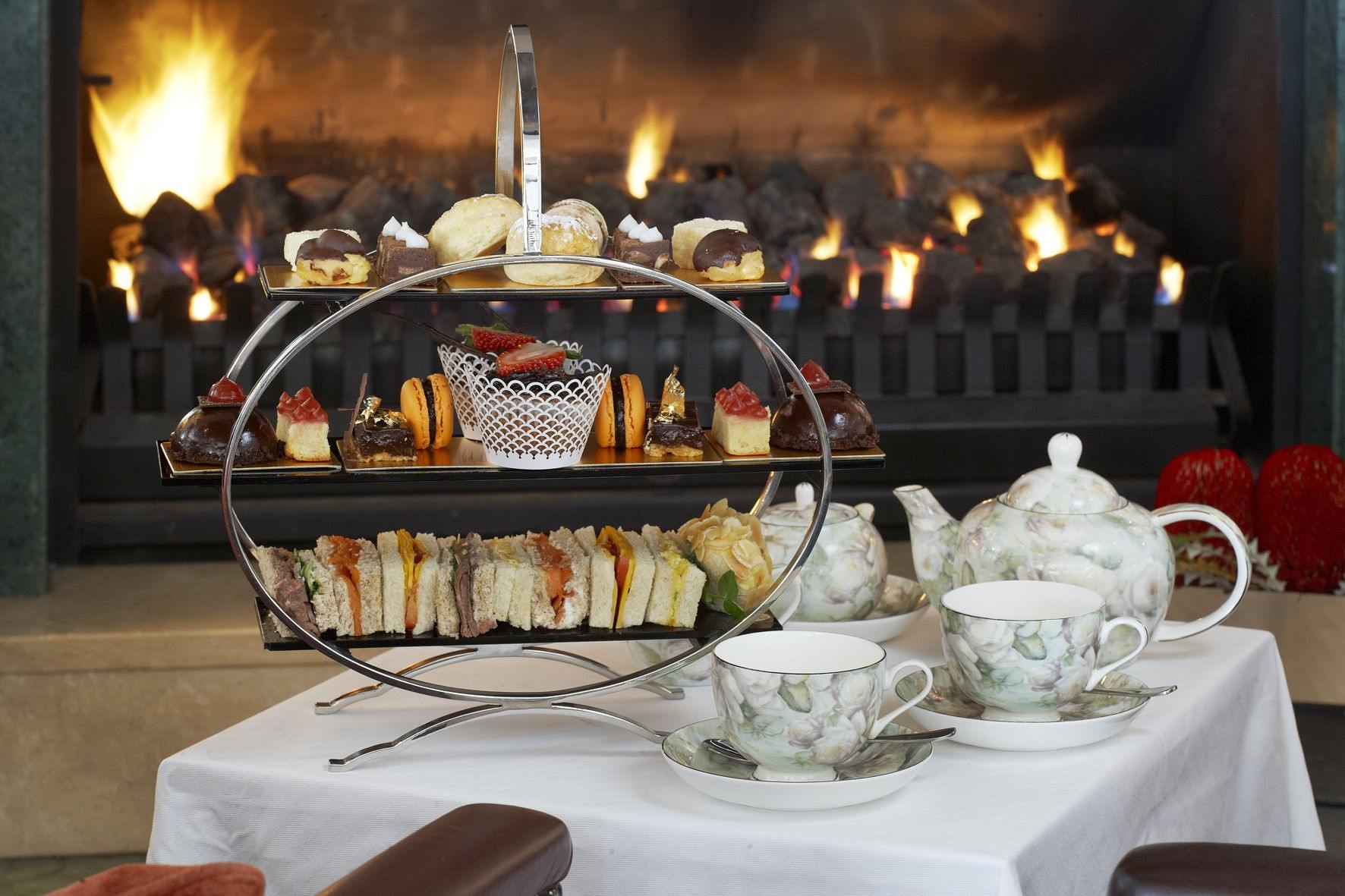 A table set with tea and cakes by a fireplace