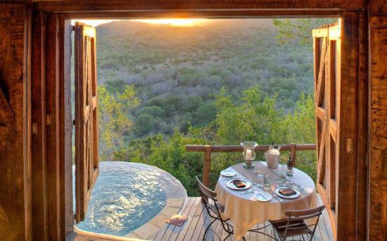 Blick von einer Terrasse mit Erfrischungspool auf das malerische Phinda Game Reserve bei Sonnenuntergang