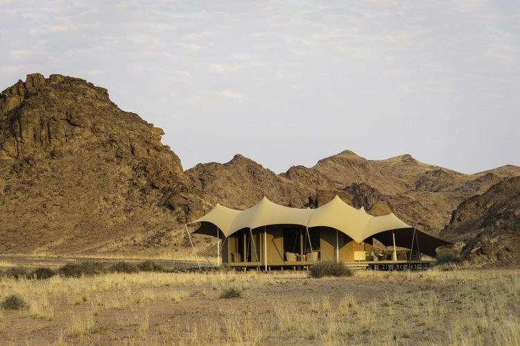 Ein Camp in der Wüste, dahinter eine Bergkulisse