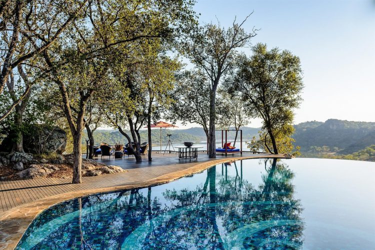 Ein Pool auf einer Terrasse, dahinter der Wald