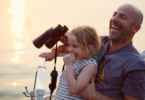 Vater mit Tochter hält auf Pirschfahrt Fernglas in der Hand