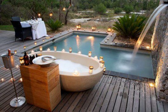 Lichter rund um Außenbadewanne und privaten Swimmingpool der Londolozi Private Granite Suites