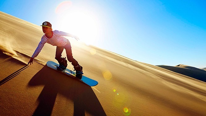 Surf sur les dunes de Namibie, au soleil couchant.