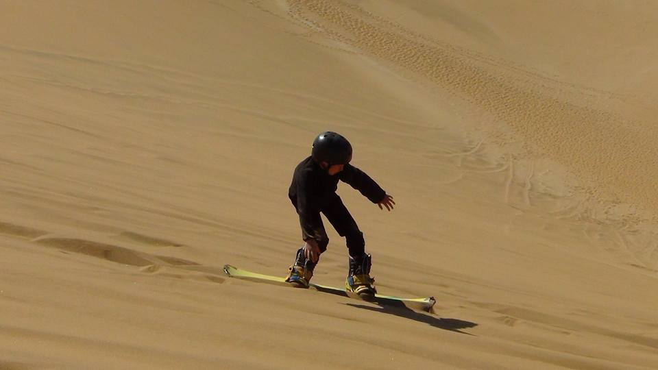 Kid sliding on a dune slope