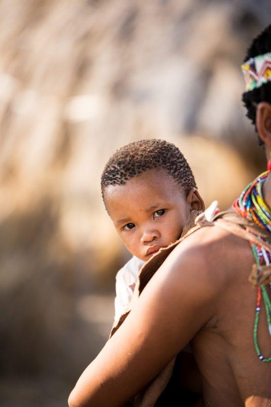 African child hanging onto mother