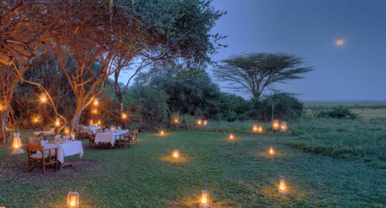 Ein Dinner in der Masai mara am Abend, helle Kerzen leuchten im Gras