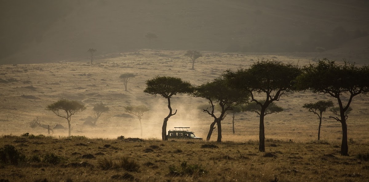 Um veículo de safári se aproxima no horizonte na Reserva Nacional Masai Mara