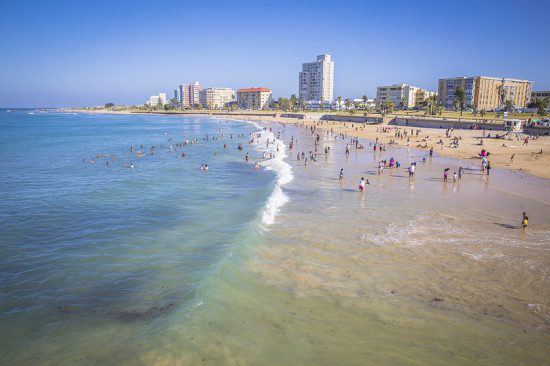 Menschen am Sandstrand von Port Elizabeth mit Hotels im Hintergrund - Garden-Route-Reise