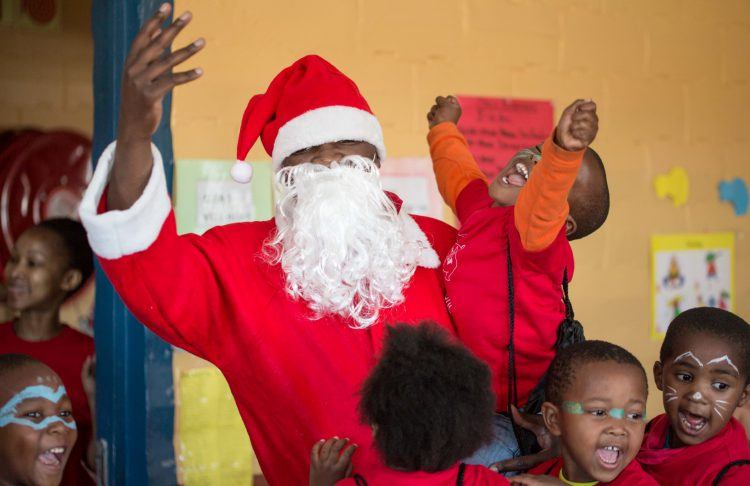 Enfant riant aux écltas dans les bras du père Noël lors de la visite des Rhinos au centre Khumbulani à Khayelitsha