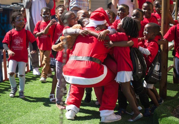 Père Noël offrant des cadeaux à des enfants dans le centre de Khumbulani dans le township de Khayelitsha