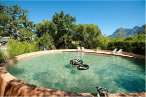 Piscine extérieure turquoise et montagnes en arrière plan à Babylonstoren.