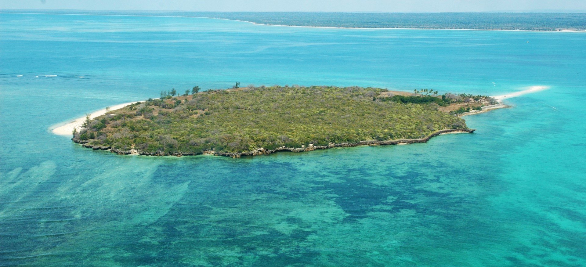 Eine grün bewachsene Insel im türkisblauen Ozean vor Mosambik