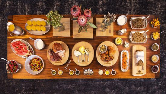 A table set with a variety of breakfast items; fruit salad, croissant, meat and cheese 