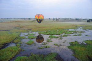 Ein bunter Heißluftballon fliegt über die traumhafte Landschaft Sambias