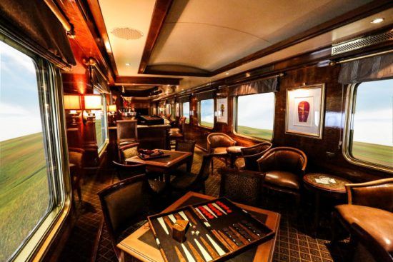 Die gemütliche Lounge des Blue Train mit großen Fenstern und dunklen Möbeln