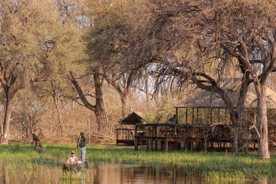 Personen unternehmen eine Kanufahrt auf Gewässern vor dem Khwai Tented Camp