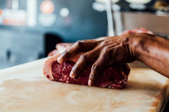 Eine Person bereitet ein Steak auf einer Anrichte zu