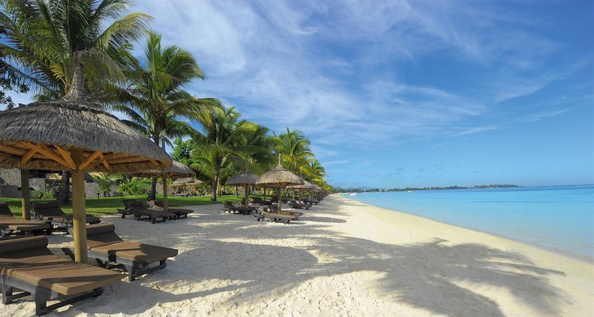 Weicher Sandstrand mit Palmen und Sonnenliegen an der Grand Baie von Mauritius