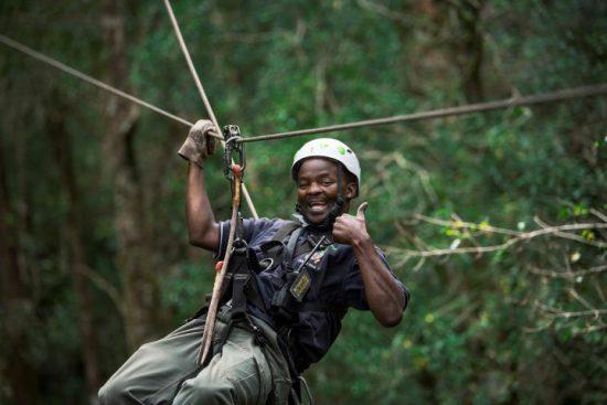 Ein Mann hebt den Daumen beim Ziplining im Wald an der Garden Route