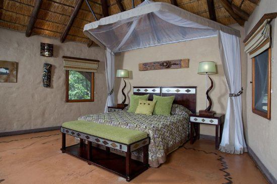 Ein Doppelbett mit Moskitonetz in einer traditionellen Safari-Lodge