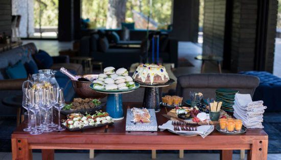 Eine große Auswahl an leckeren Snacks und Getränken auf einem Tisch vor einer Luxuslodge - SIlvan Safari