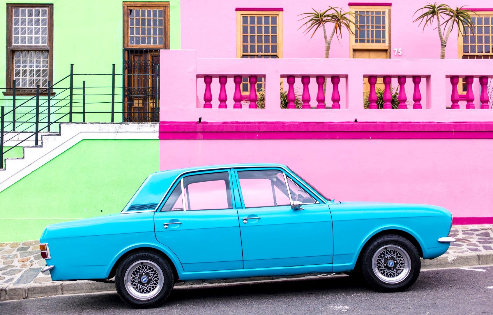 Voiture bleu électrique face aux maisons colorées de Bo Kaap au Cap.