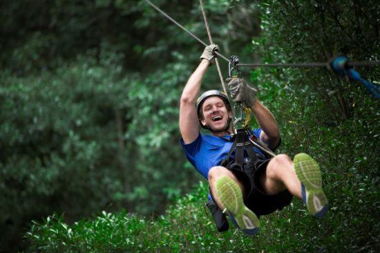 Ein junger Mann hat großen Spaß beim Ziplining im Wald