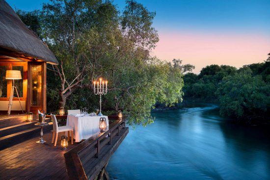 Die Royal Chundu Zambezi Island Lodge mit abendlicher Beleuchtung bei Sonnenuntergang