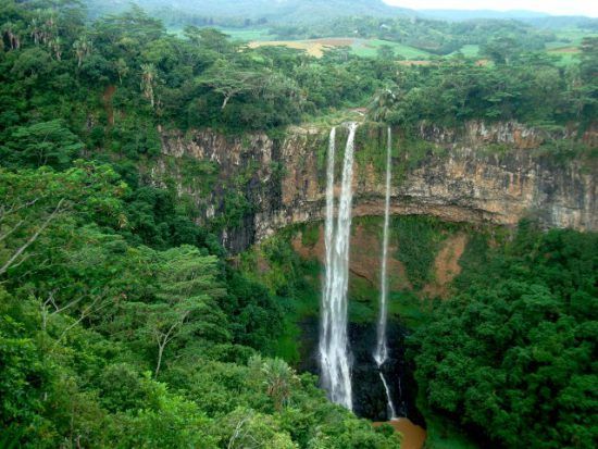 Ein schmaler Wasserfall in einer grün-tropischen Landschaft