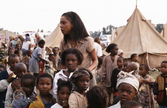 Atriz Sophie Okonedo cercada por crianças no set de "Hotel Ruanda"