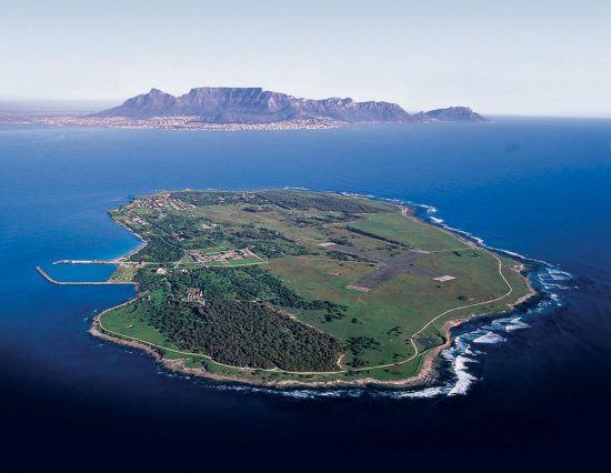 Eine Insel umrandet von Meer, dahinter erkennt man den Tafelberg