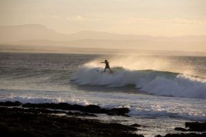 Un surfista en la costa de Jeffrey's Bay, Sudáfrica