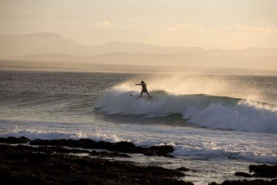 Surfista en la costa de Jeffrey's Bay, Sudáfrica