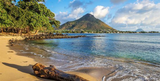 Ein goldener Strand mit Palmen und Bergen im Hintergrund