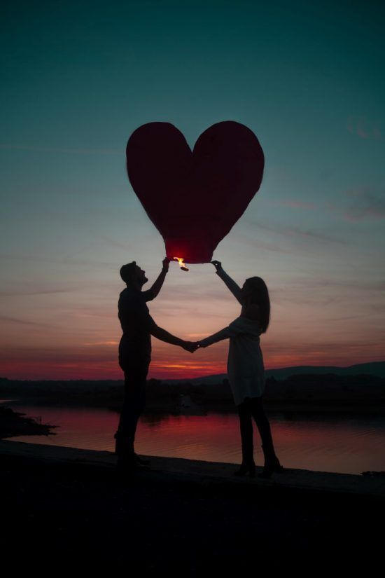 eine Frau und ein Mann halten einen Herzballon in die Luft