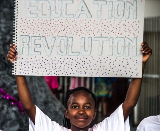 Un élève de Good Work Foundation portant une pancarte "Education Revolution".