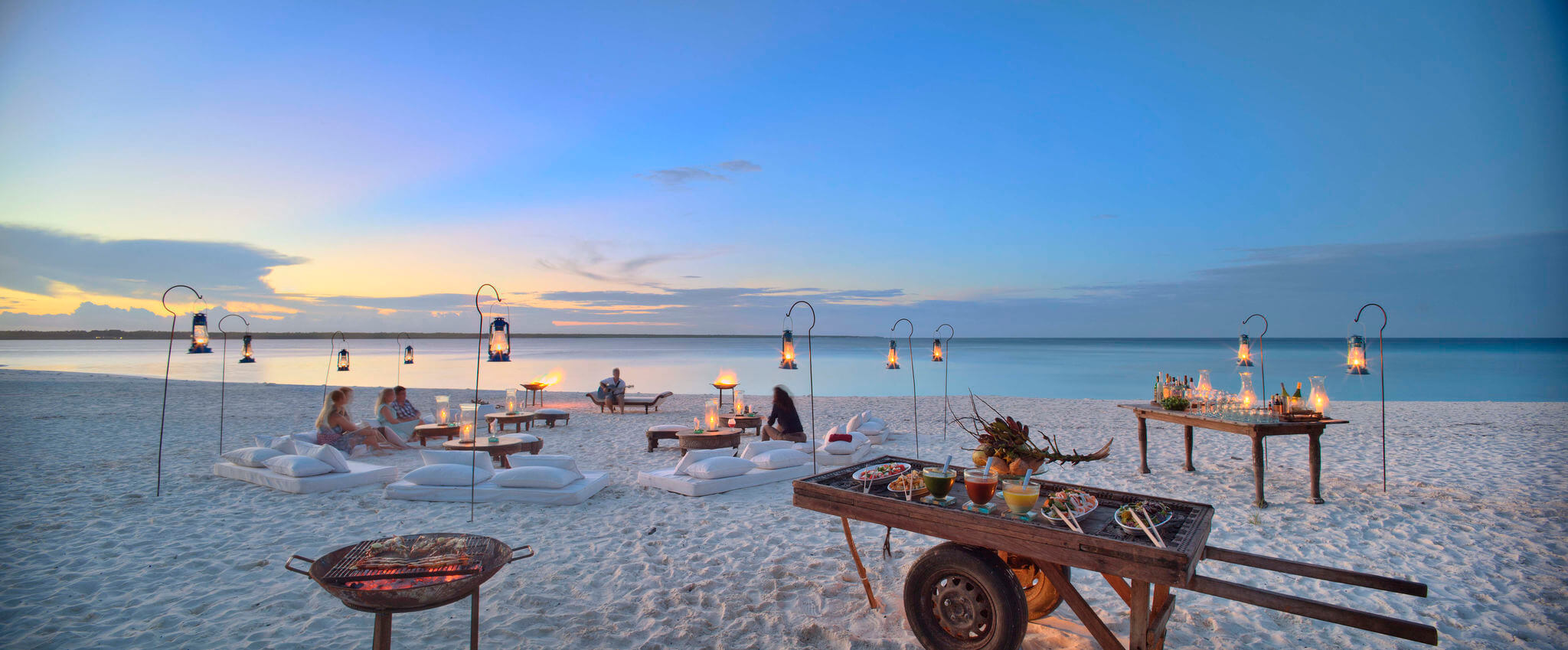 auf einem Strand sind Tische und Lampen aufgestellt