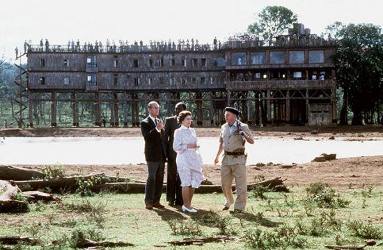 Rainha Elizabeth em pé em frente ao Hotel Treetops em uma visita ao Quênia. 