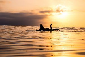 Una surfista se relaja en su tabla al atardecer