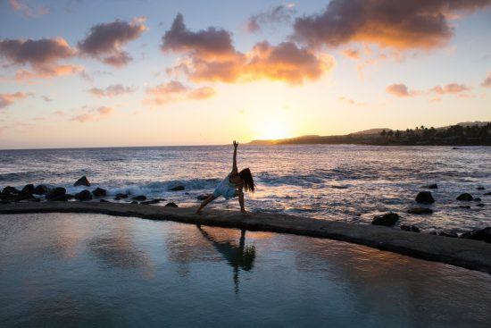 The sun sets behind a person in a yoga pose