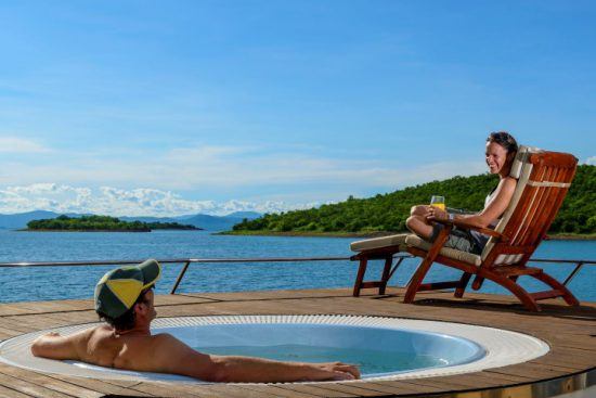 Mann erfrischt sich an Bord im Pool und seine Frau sonnt sich