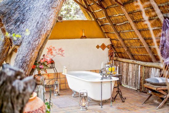 A freestanding bath under a thatched roof