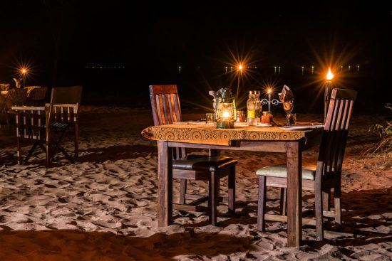 Ein Tisch im Kerzenschein am Strand vorm Changa Safari Camp