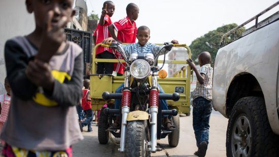 Un enfant sur une grande moto d'adulte dans les rues de Brazaville au Congo.