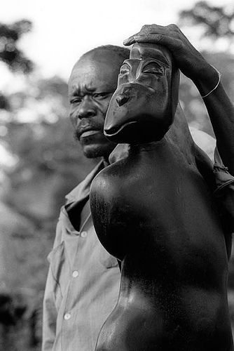 Samwell Chriume poses next to one of his sculptures at Tengenenge sculptors community