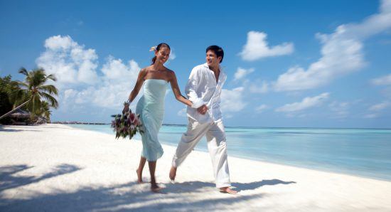 Casal caminha pela praia na ilha de Kuda Huraa, durante estadia no Four Seasons Resort, em Maldivas