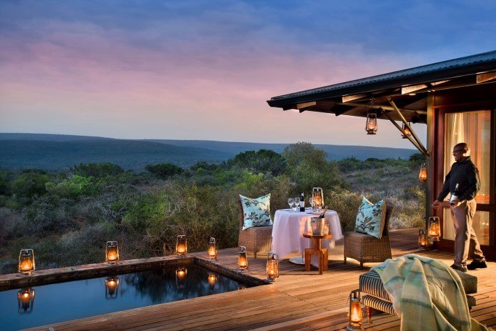 Ein gedeckter Tisch neben einem Pool in einer Suite der Kwandwe Ecca Lodge bei Sonnenuntergang