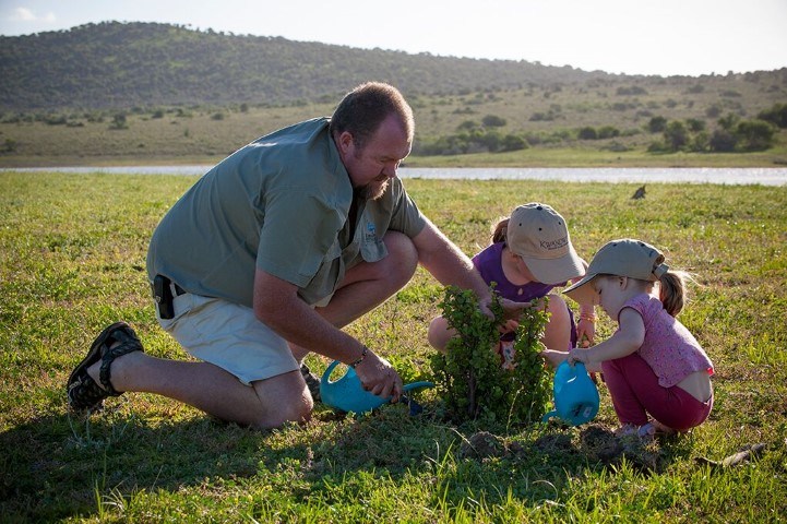 Vater pflanzt mit Töchtern einen Speckbaum im Kwandwe Private Game Reserve