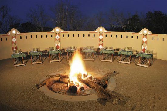 Boma-Dinner in der Elephant Plains Game Lodge mit Lagerfeuer und festlich dekorierten Tischen